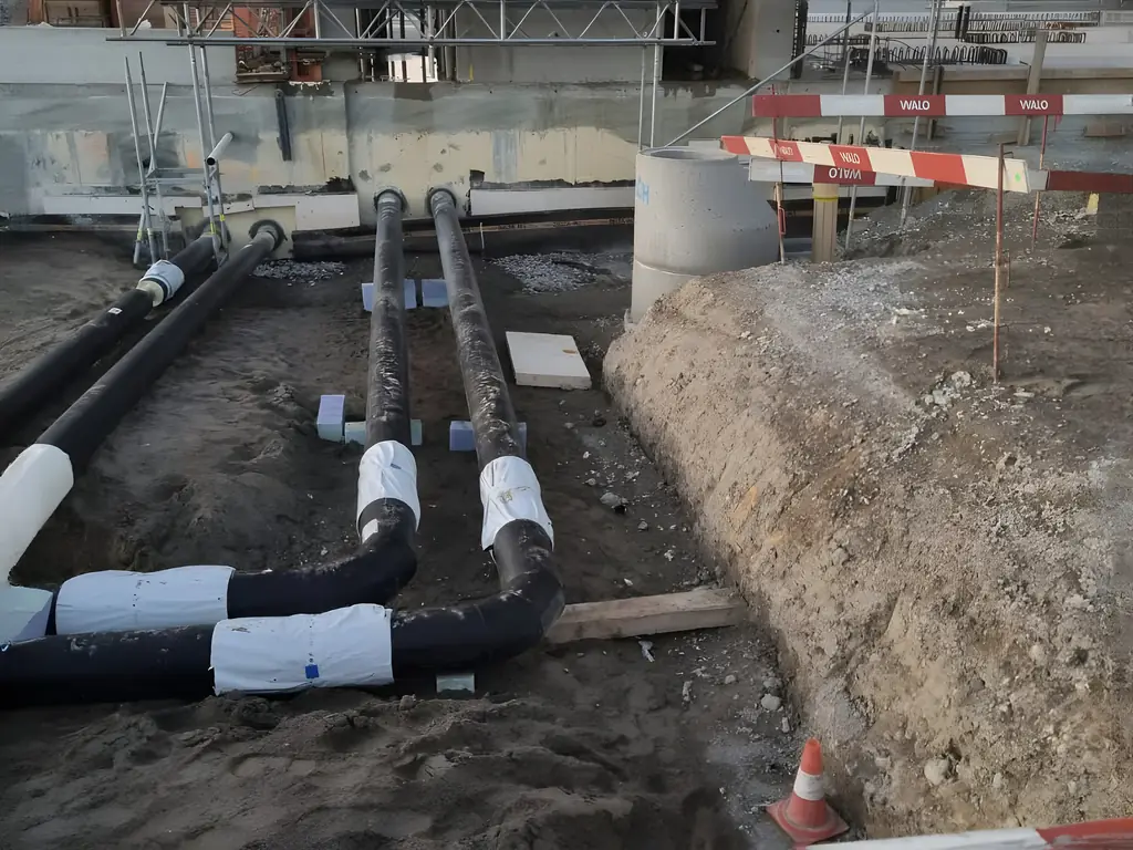 Leitungen in einem Graben neben einem Neubau